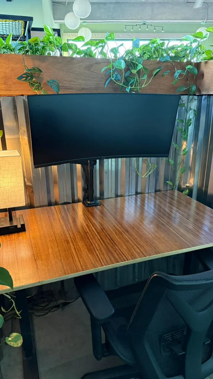 monitor curvo de 34" en el área de cubículos sobre un escritorio de altura ajustable