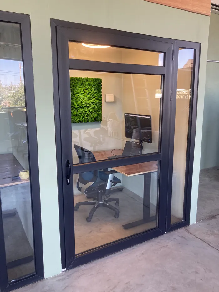 A well-lit meeting room with a long table, multiple chairs, and a large window providing natural light.
