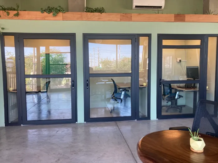 A well-lit meeting room with a long table, multiple chairs, and a large window providing natural light.